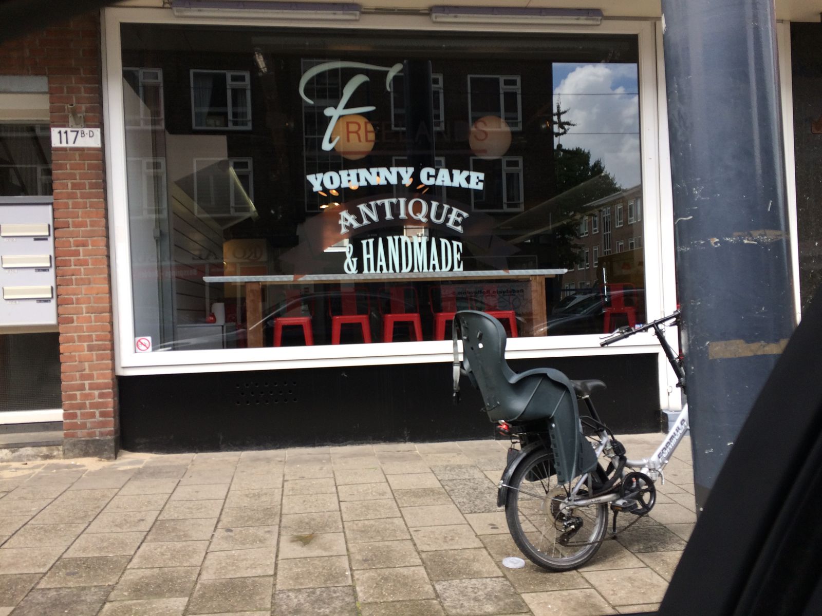 Detail raambelettering Yohnny Cake cafe — handgetekende logoletters en Antique & Handmade tekst